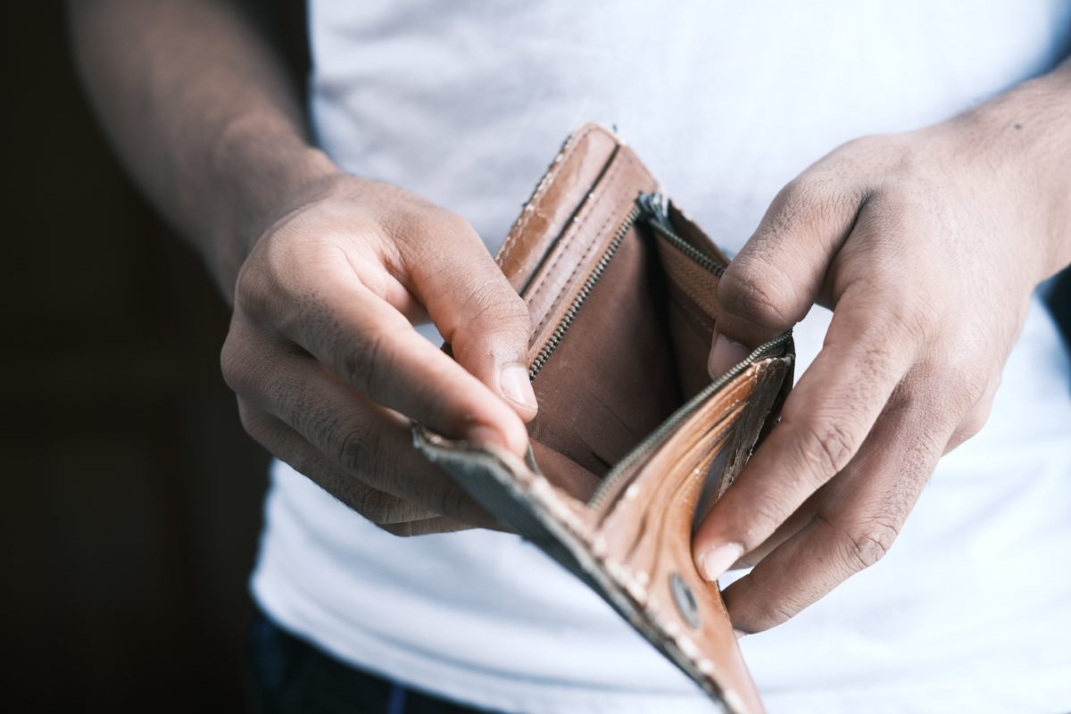 A man's hands hold open an empty brown wallet.